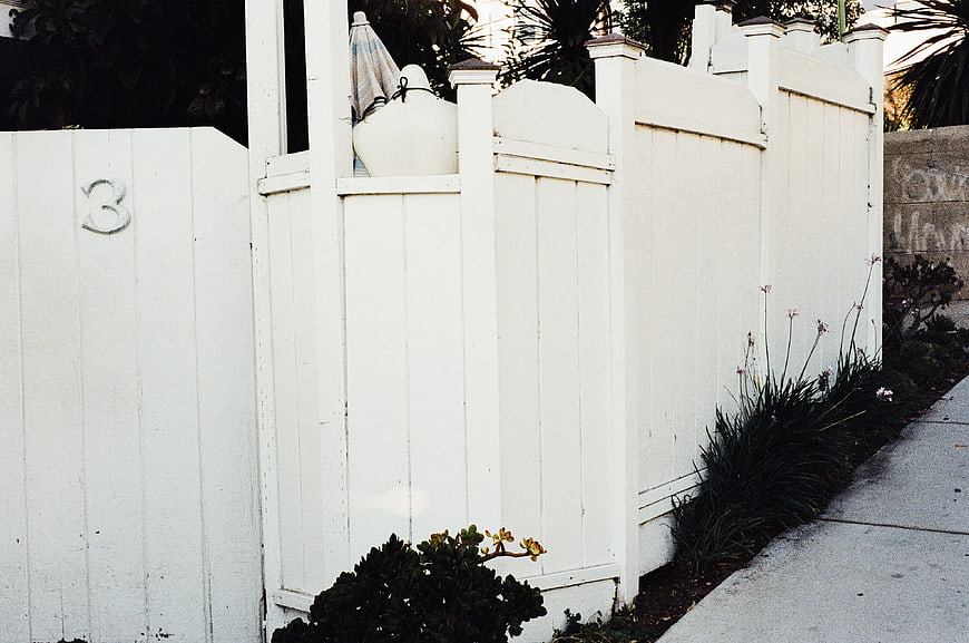 White wooden fence with number 3 and sidewalk
