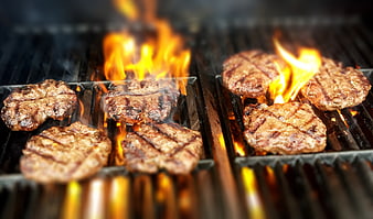 Juicy burger patties grilling with flames on barbecue
