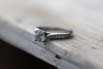 Close-up of diamond engagement ring on rustic wood