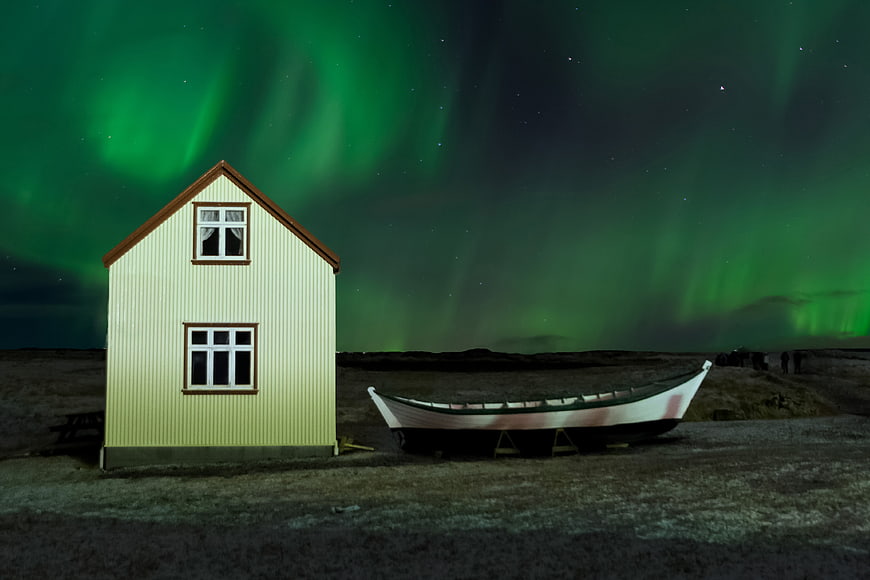 Small Yellow House And Boat Under Green Aurora Borealis Night Sky