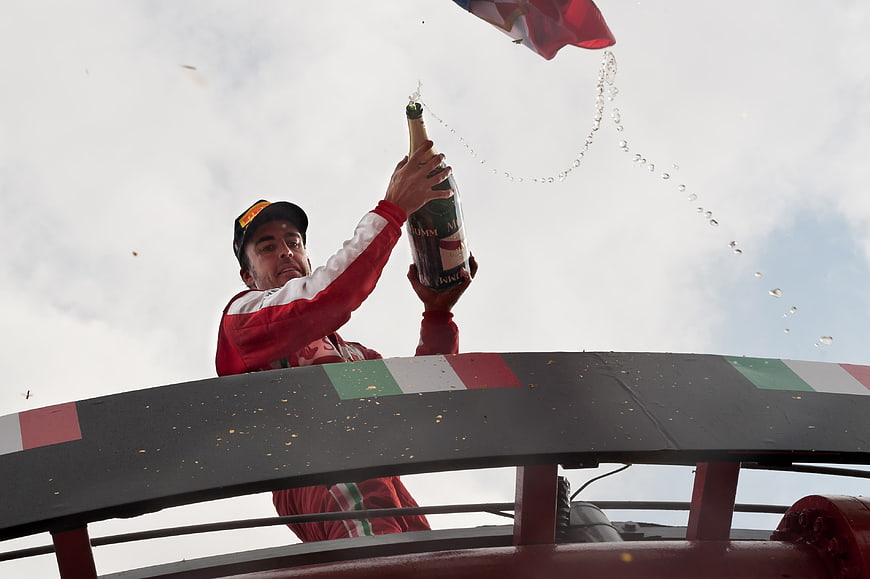 Race driver celebrating victory with champagne spray on podium