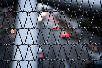 Close-up of hexagonal wire mesh fence with blurred city lights