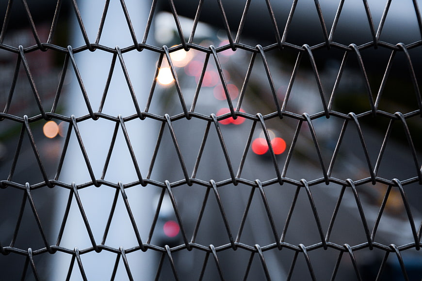 Close-up of hexagonal wire mesh fence with blurred city lights