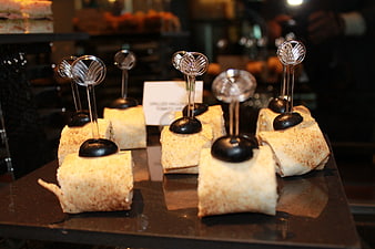 Catering pinwheels with decorative picks on a black tray