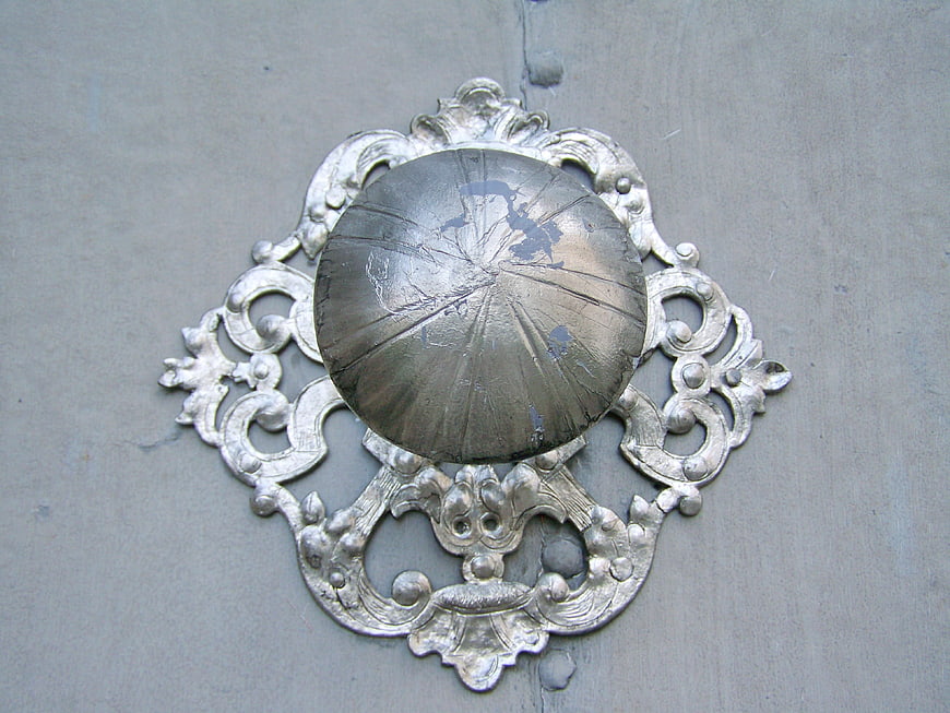Vintage ornate silver door knocker on gray wooden door