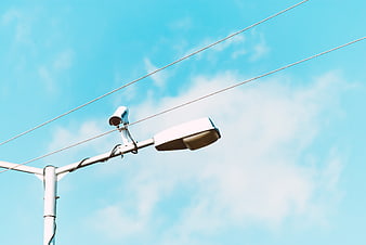 CCTV Camera on Street Lamp Against Blue Sky