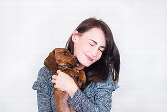 Happy woman hugging dachshund dog on white background