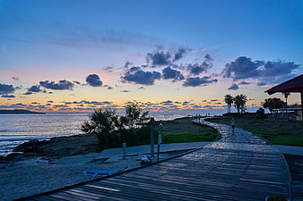 Wooden boardwalk path along beach at sunrise with runner