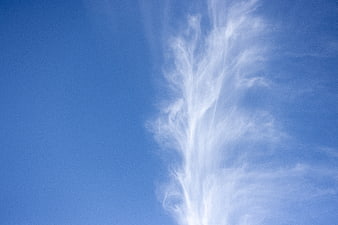 Wispy white clouds against a clear blue sky background