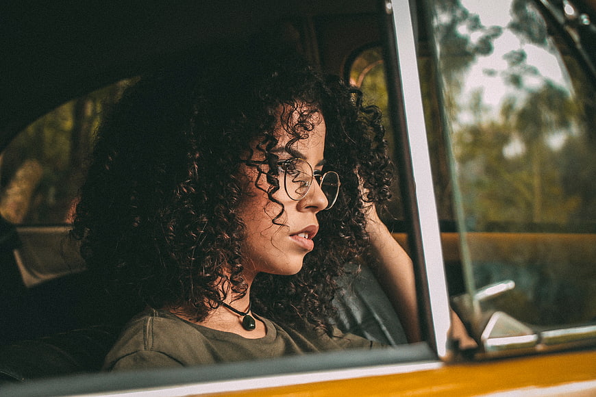 Woman with curly hair looking out of vintage car window