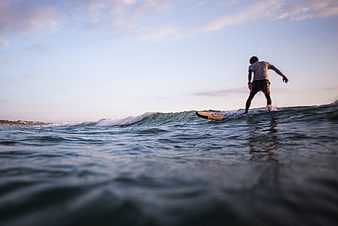Man Surfing Ocean Waves at Dusk