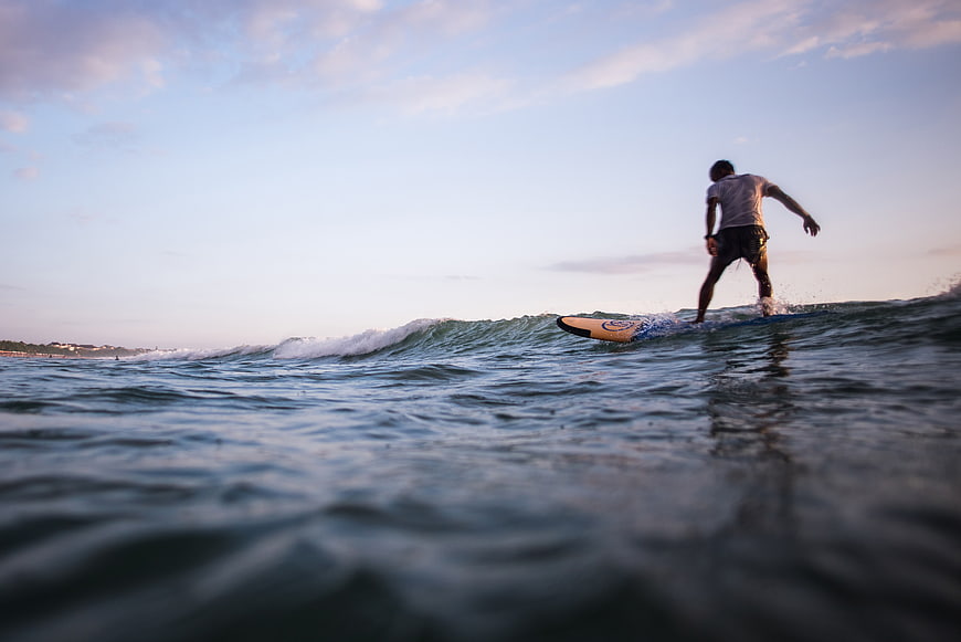 Man Surfing Ocean Waves at Dusk