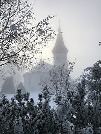 Snowy church spire emerging from thick winter fog