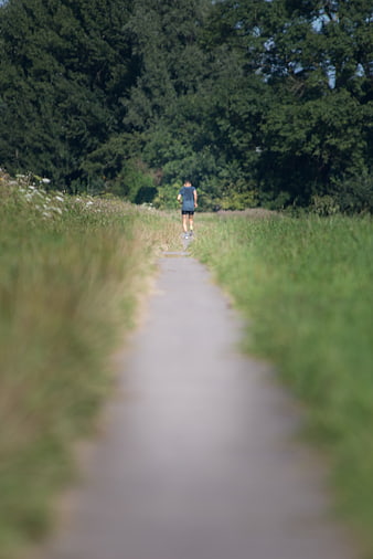 Man Running on Path Through Green Forest