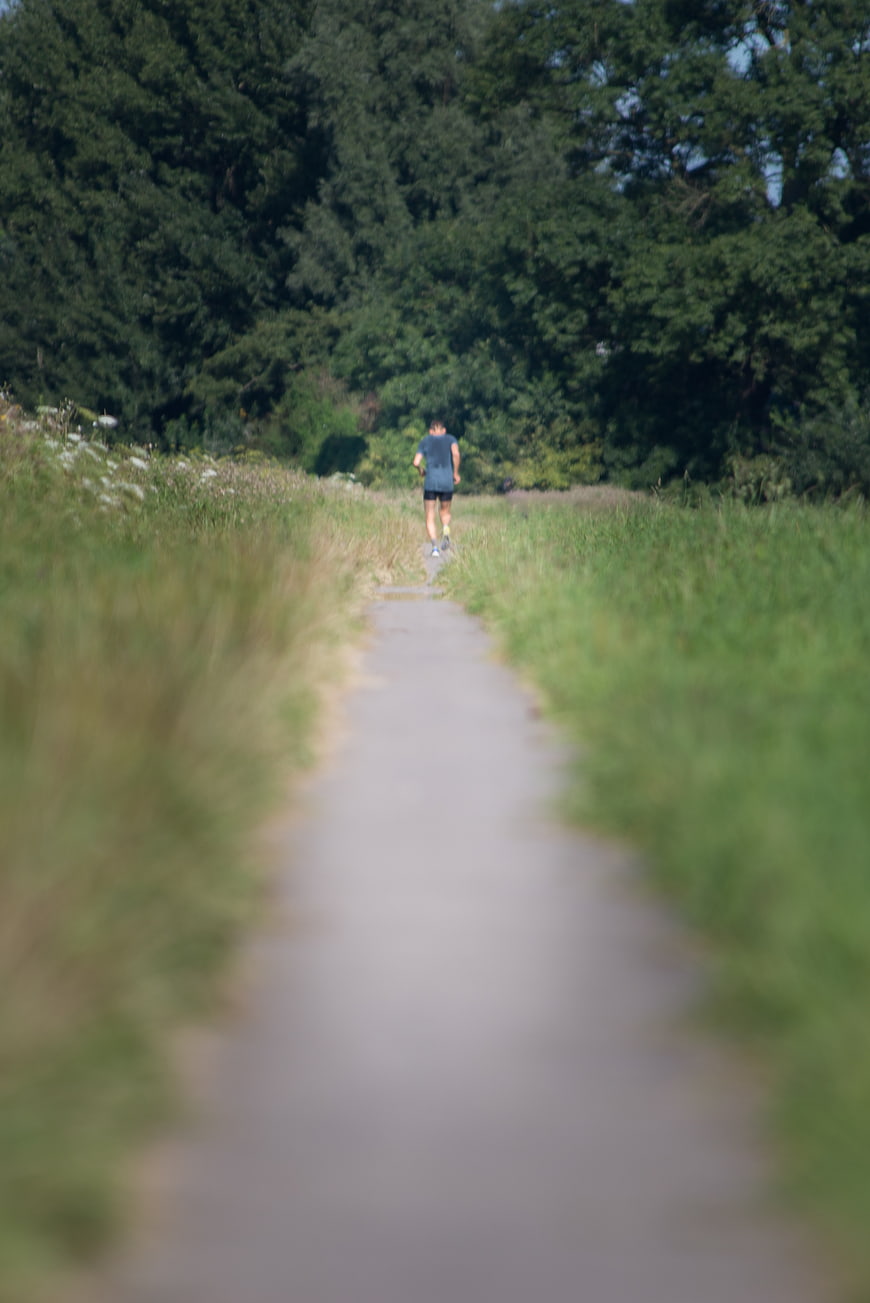 Man Running on Path Through Green Forest