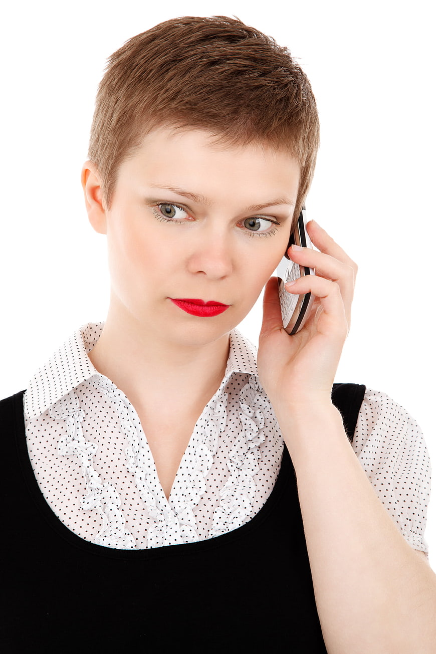 Serious woman with short hair talking on smartphone