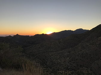 Sunset over rugged mountain range with silhouetted hills