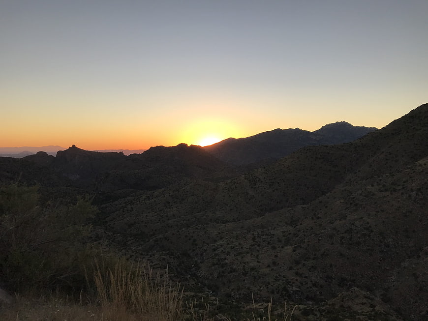 Sunset over rugged mountain range with silhouetted hills
