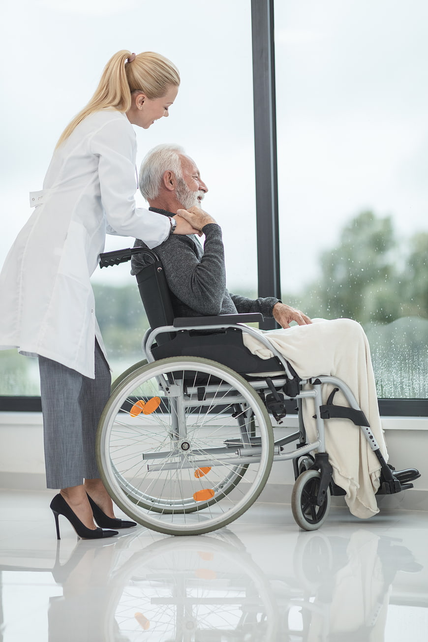 Female doctor comforting senior male patient in wheelchair
