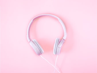 White headphones on pastel pink background