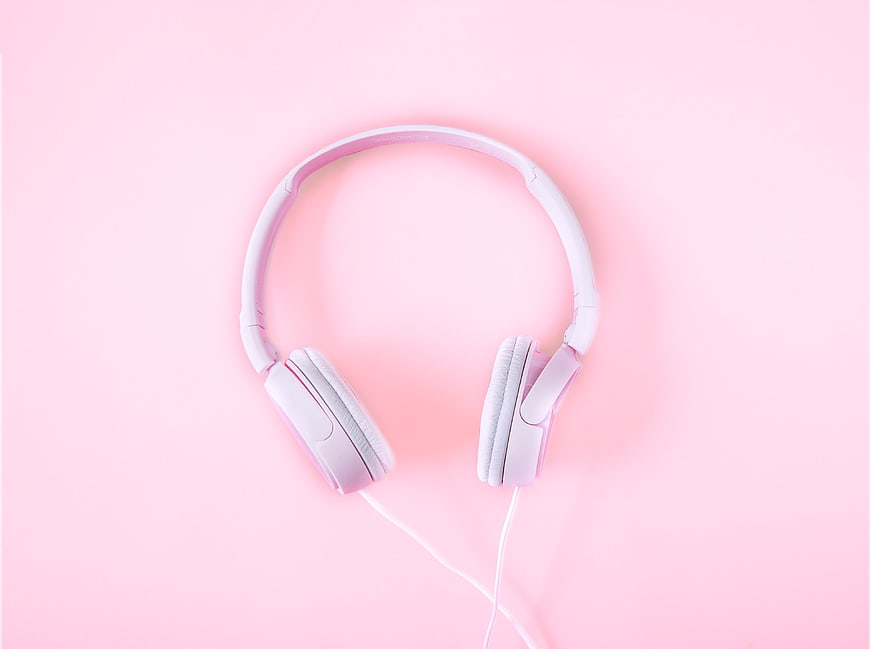 White headphones on pastel pink background