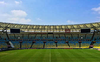 Wide view of empty soccer stadium with blue and yellow seats