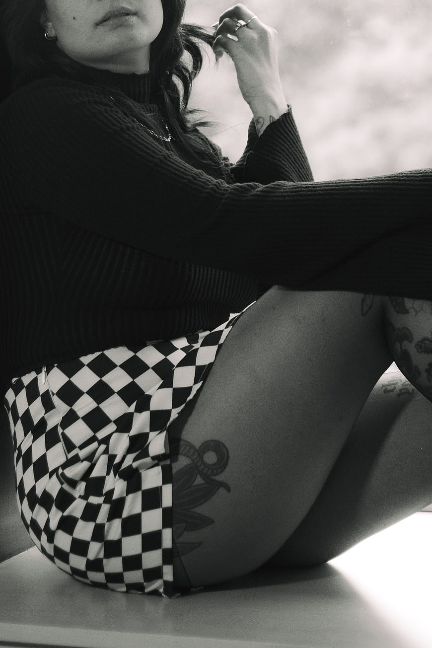 Black and white portrait of tattooed woman in checkered shorts