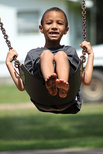 Smiling young boy sitting on a swing outdoors