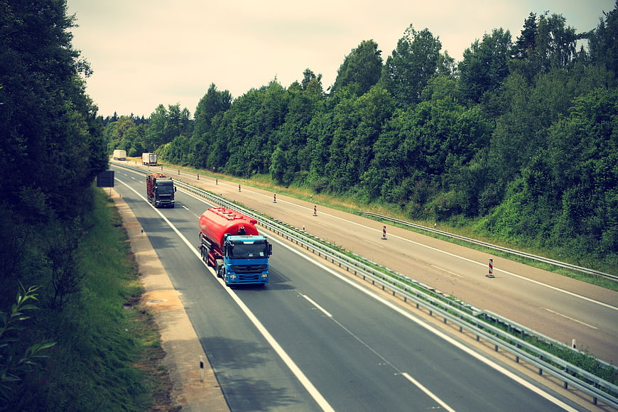 Blue tanker truck driving on highway with road construction