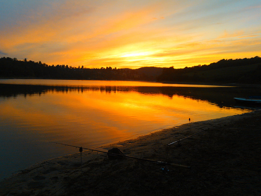 Fishing Rods on Sandy Shore at Golden Sunset