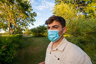 Young man wearing blue medical mask in park
