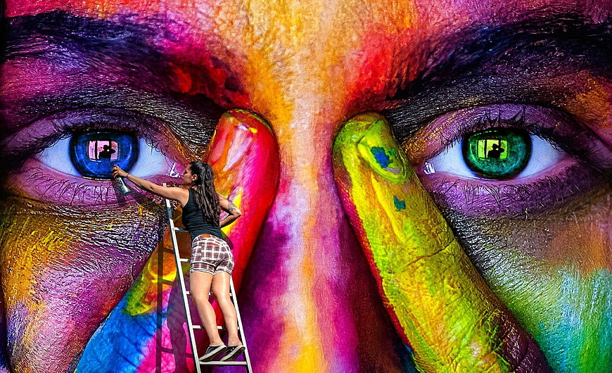 Woman painting colorful mural on ladder