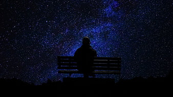Silhouette of Man Sitting on Bench Under Starry Night Sky