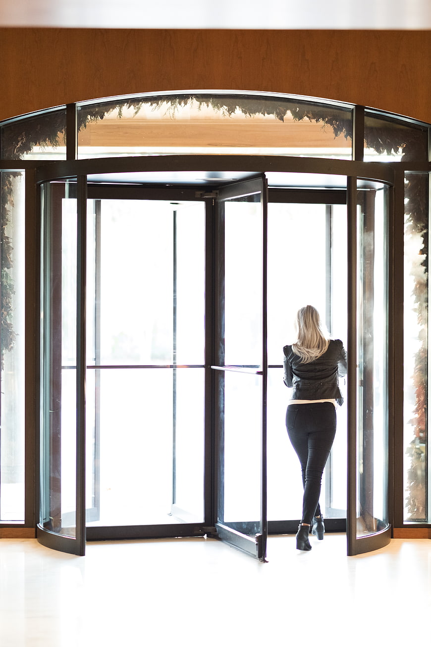 Woman in Black Jacket Exiting Modern Revolving Door