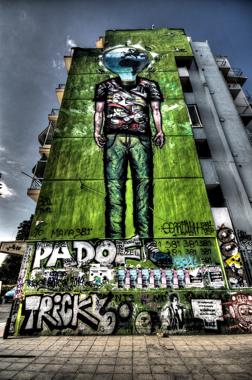 Urban street art mural of headless figure on green wall