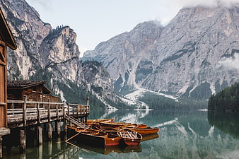 Wooden boats docked at a serene alpine lake with mountains