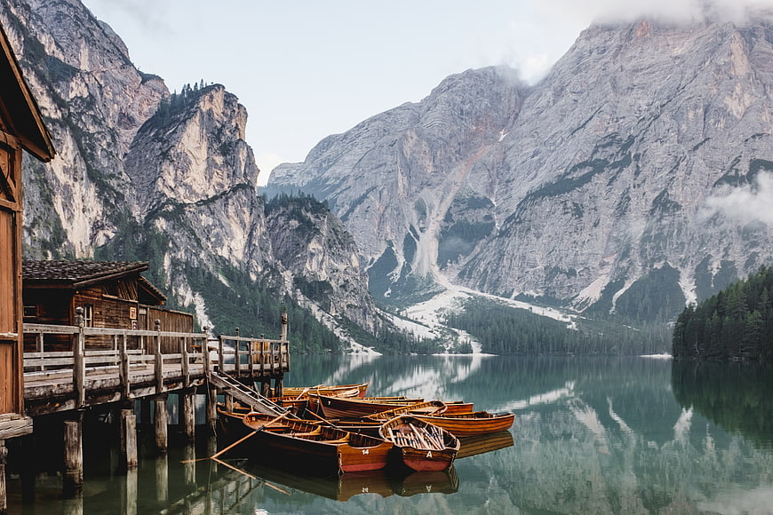 Wooden boats docked at a serene alpine lake with mountains