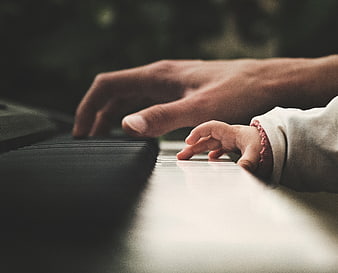 Adult and baby hands playing piano keys together