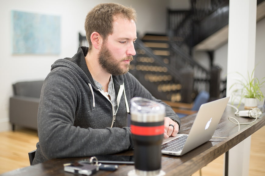 Bearded man working on laptop at home office desk