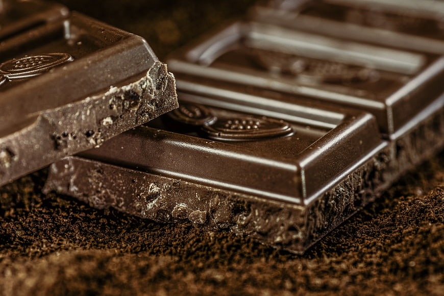 Close-up of dark chocolate pieces on ground coffee