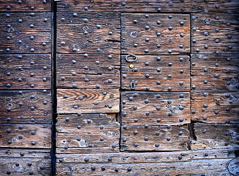 Close-up of weathered wooden door with metal studs and lock