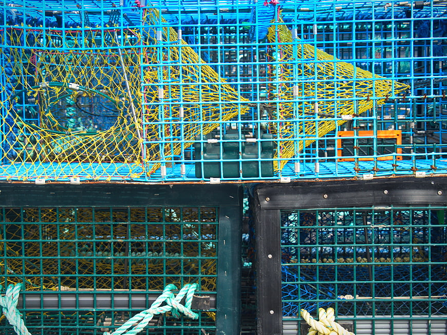 Stacked blue and green lobster traps with yellow netting