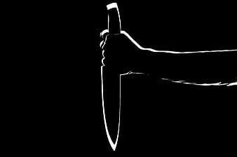 Silhouette of hand holding knife on black background