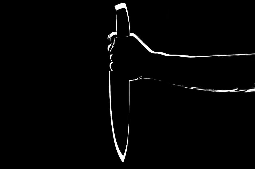 Silhouette of hand holding knife on black background