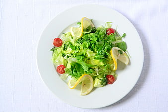 Fresh Green Salad with Lemon and Tomatoes on White Plate