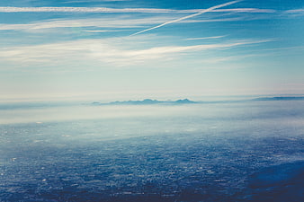 Aerial View of City Over Sea of Fog with Distant Mountains