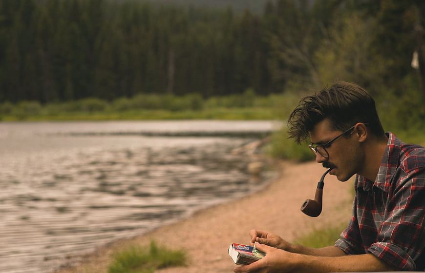Man smoking pipe by river in nature