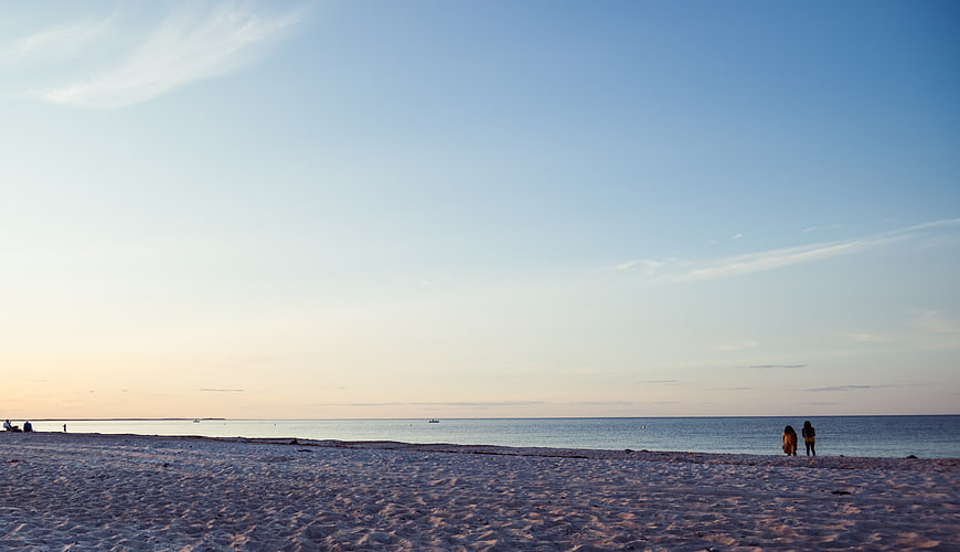 Wide Beach Landscape with People at Sunset and Blue Sky