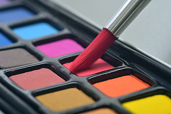 Close-up of paintbrush dipping into red watercolor palette