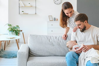 Happy Parents with Newborn Baby on Sofa
